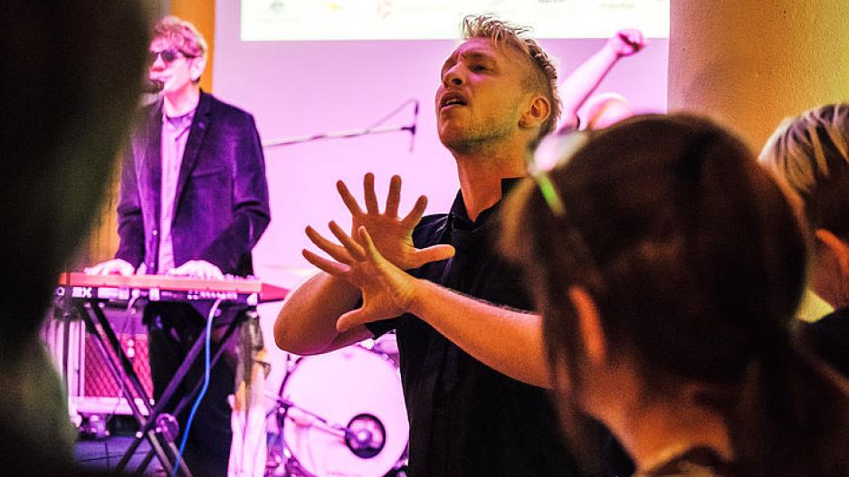 Konzert der Band Rudely Interrupted Im Hintergrund spielt die Band Rudely Interrupted, im Vordergund übersetzt ein Dolmetscher den Songtext in Australische Gebärdensprache