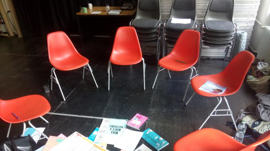 Workshop Machtkritische Sprache Orangefarbene Stühle stehen im Kreis, Arbeitsmaterialien liegen in der Mitte
